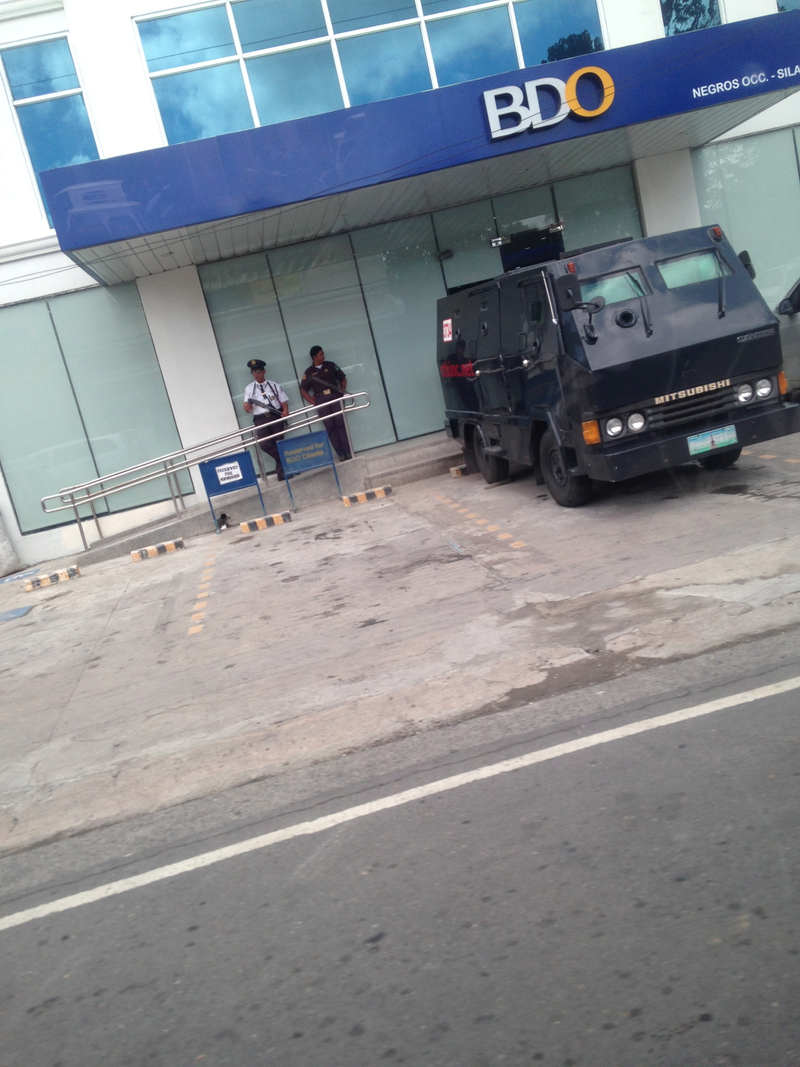 An Armored car and 2 armed security guards outside of a bank in negros occidental